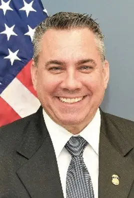 A man in suit and tie next to an american flag.