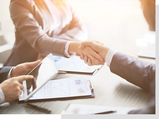 Two people shaking hands over a table.