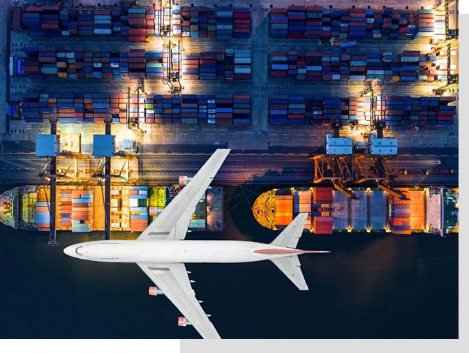 An airplane flying over a large port filled with lots of cargo.