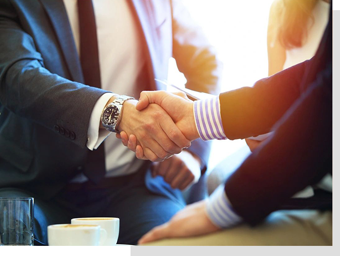 Two people shaking hands over a table.