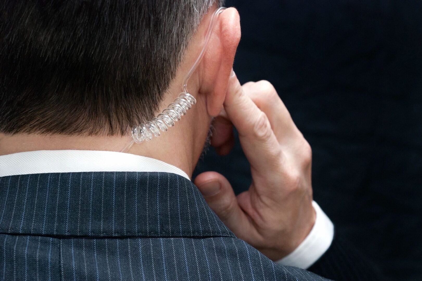 A man in a suit is holding his ear